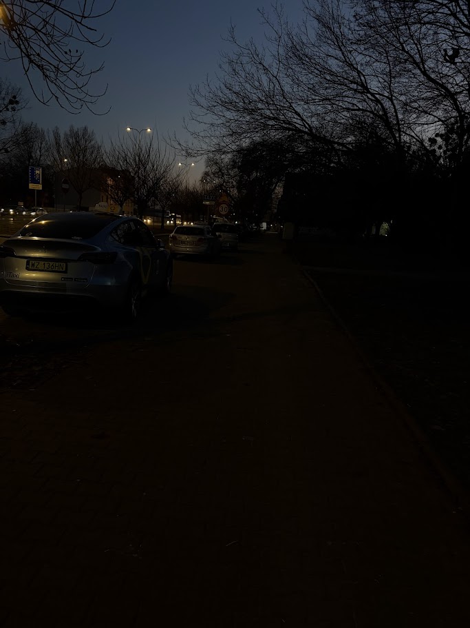 Parkujące samochody na chodniku - miejsce nieoświetlone